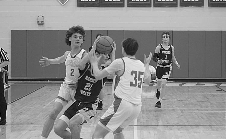 William Jorden (21) looks to get rid of the basketball while being defended by two Central Private players in Sacred Heart’s 57-43 loss in the first round of the Division IV Select playoffs. (Gazette photo by Tony Marks)