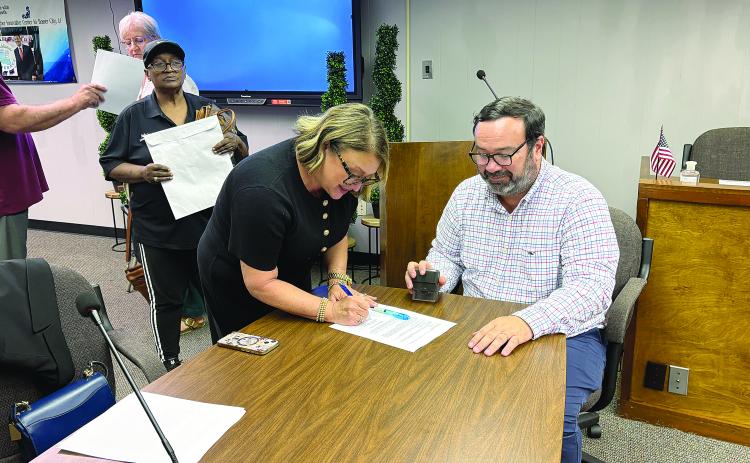 Cheri Fontenot (center) is pictured as she signs her contract to officially become the new school superintendent. Seated is Assistant District Attorney Jacob Fusilier, who notarized the contract. Also pictured on the left is Evangeline Parish School Board Vice President Sheila Joseph. (Gazette photo by Tony Marks)