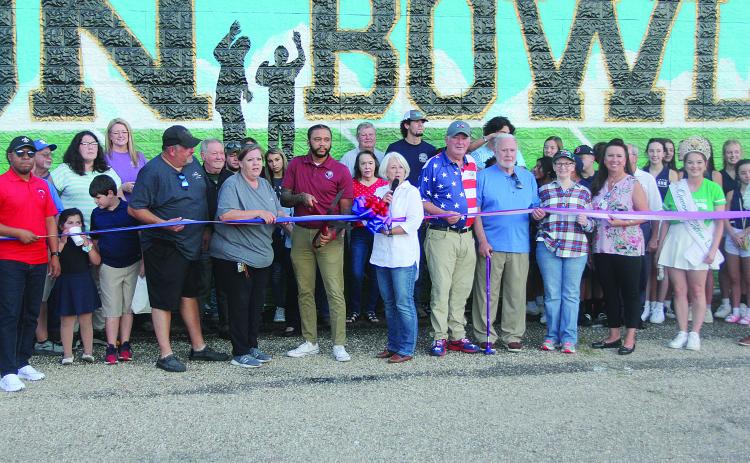 Among those pictured at the Tee Cotton Bowl mural dedication ceremony are (from left) Chris and Connie Lamke, Thaddaeus Arvie, Dr. Gwen Fontenot, Tim Fontenot, Ronnie and Joan Landreneau, Renee Brown, and Queen Cotton Shelbi Rials. (Gazette photo by Tony Marks)