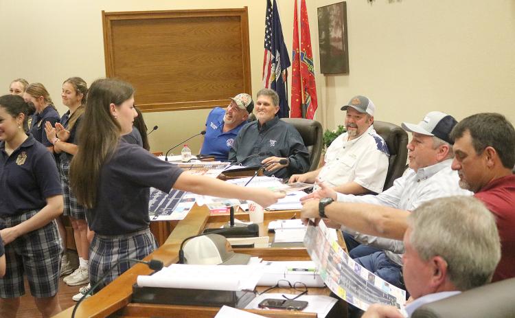 Kali Shiver (left) hands Evangeline Parish Police Juror Tim Causey (right) a basketball schedule poster that was signed by the members of the Sacred Heart girls’ team that advanced to the state basketball tournament for the first time in school history. All police jurors received a similar poster. Also pictured (from top on the right) are jurors Keith Saucier; Kevin Veillon, vice president; Bryan Vidrine, president; Ryan Ardoin; and Brent Guillory. (Gazette photo by Tony Marks)