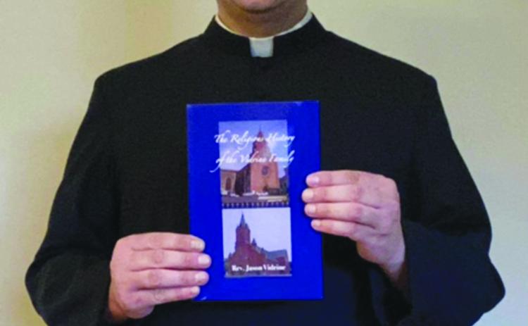 Father Jason Vidrine poses with a copy of his book The Religious History of the Vidrine Family. (Photo courtesy of Father Jason Vidrine)