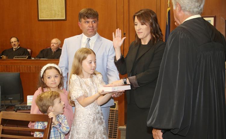 Laura Rougeau Garcille recites her oath of office delivered by State Supreme Court Judge James Genovese on Wednesday in the St. Landry Parish Courthouse. With her is her husband, Brett, and children, Emmy, 9, holding a Bible, Riley 7 and John Roth, 4. Seated in the background are District Judges Gregory Doucet and James Dotherty. (LSN photo by Harlan Kirgan)