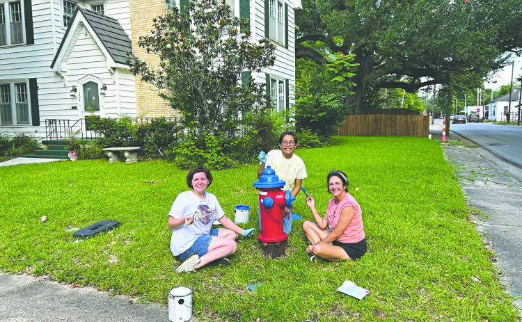 HYDRANTS GET A PATRIOTIC FACELIFT - From left, Kate LaCaze, Sarahi Sawtelle and Nina David are shown as they paint one of six fire hydrants along Magnolia Street. (Photo courtesy of Nina David)