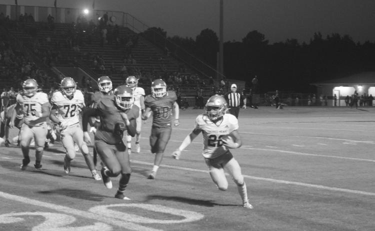 Trojan speedster Ike Perry (22) tries to elude a would-be tackler in Sacred Heart’s 13-0 loss to Caldwell Parish Thursday night. The Trojans now host Catholic-P.C. in a district contest. (Gazette photo by Tony Marks)