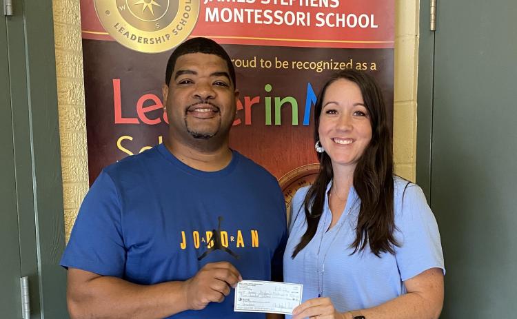 Chris Serie (left) presents a $500 donation to James Stephens Montessori Principal Melanie Bordelon for the school’s athletics program. (Photo courtesy of Melanie Bordelon)