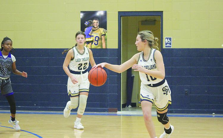 Emily Stagg (10) takes the basketball toward the net after receiving an inbound pass from Lady Trojan teammate Kali Shiver (22). (Gazette photo by Rhett Manuel)