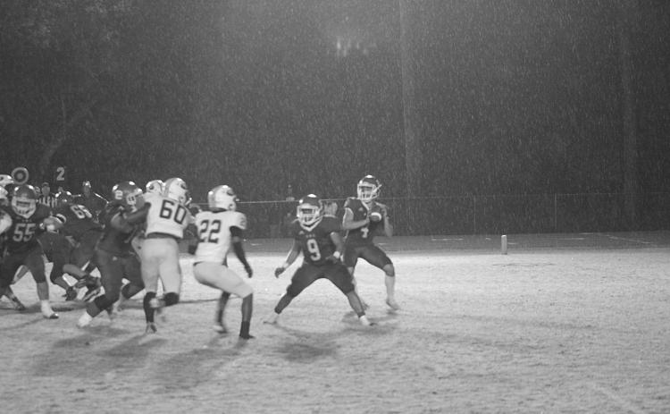 With rain falling down all around him, Basile quarterback Luc Johnson (4) drops back for a pass as Horace Edwards (9) provides a block. (Gazette photo by Rhett Manuel)