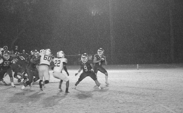 With rain falling down all around him, Basile quarterback Luc Johnson (4) drops back for a pass as Horace Edwards (9) provides a block. (Gazette photo by Rhett Manuel)