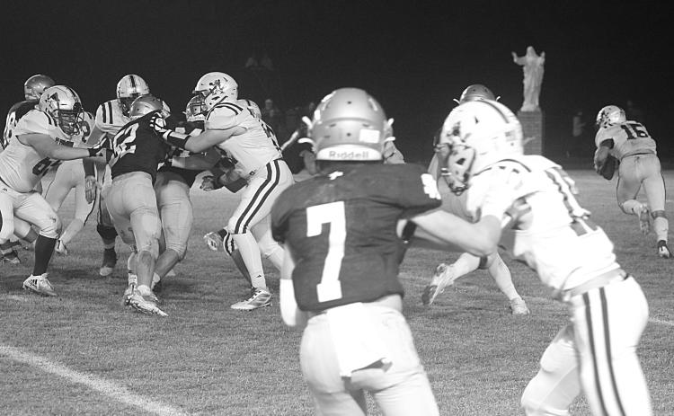 The Sacred Heart defense led by Hayden Droddy (7) and Beau St. Romain (52) combines for a stop deep inside Blue Jay territory in the Trojans’ playoff win against St. Ed’s last week. (Gazette photo by Rhett Manuel)