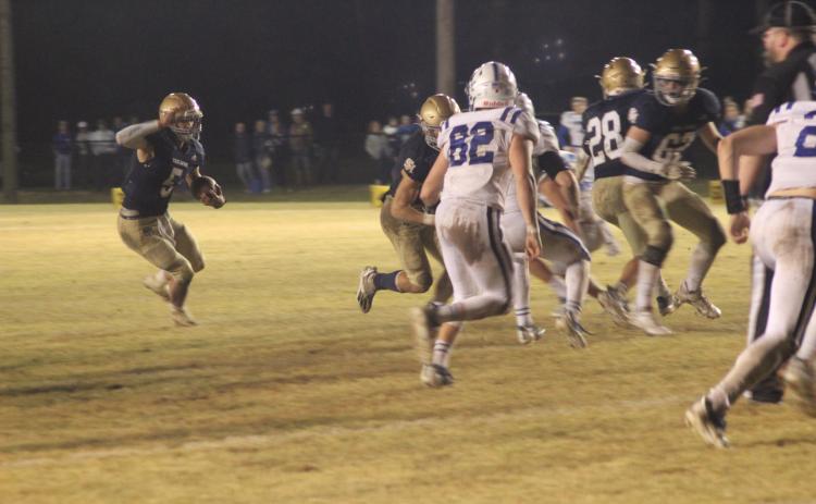 Sacred Heart quarterback Ethan Karonika (5) finds a running lane thanks to a block from his offensive line in the Trojans’ playoff win against disrtrict rival St. Edmund. (Gazette photo by Rhett Manuel)