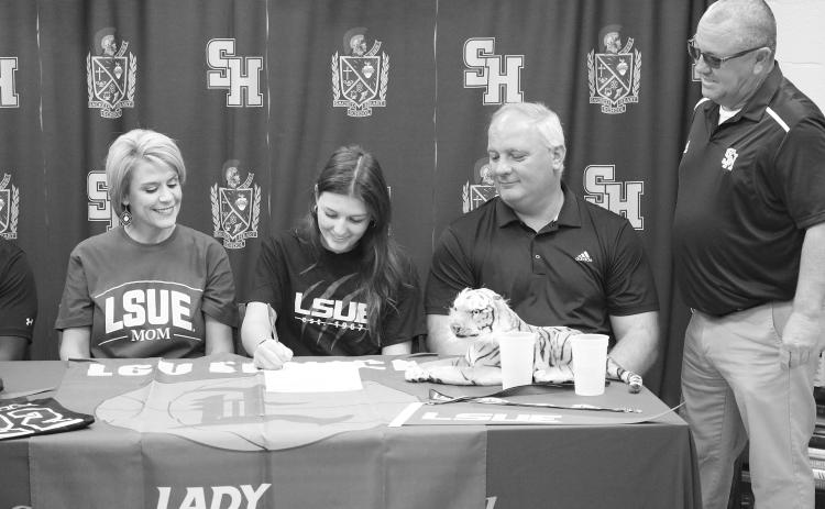 Sacred Heart’s Kali Shiver (second from left) puts pen to paper as she signs to play college basketball at LSU Eunice. Also pictured (from left) are her mother, Ashley Veillon; her father, James Shiver; and her head basketball coach, Craig Whittington. (Gazette photo by Tony Marks)