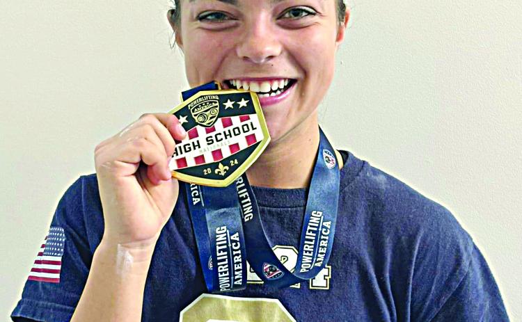 Adeline Launey shows off her medal for winning a national powerlifting meet in New Orleans. (Photo courtesy of Sacred Heart Athletics)
