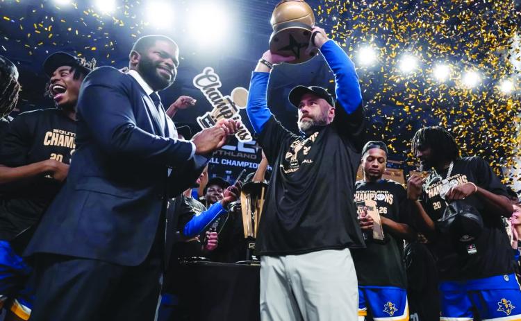 McNeese head men’s basketball coach Bill Armstrong (center) hoists the SLC Championship Trophy after the Cowboys defeated Stephen F. Austin. (Photo courtesy of Matthew Bonnette)