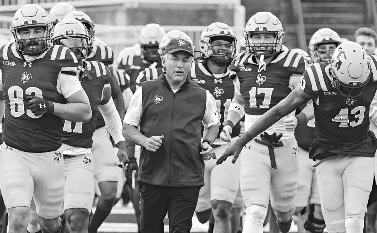 McNeese football coach Matt Viator runs onto the field with his team before a game last season. (Photo courtesy of McNeese Athletics)
