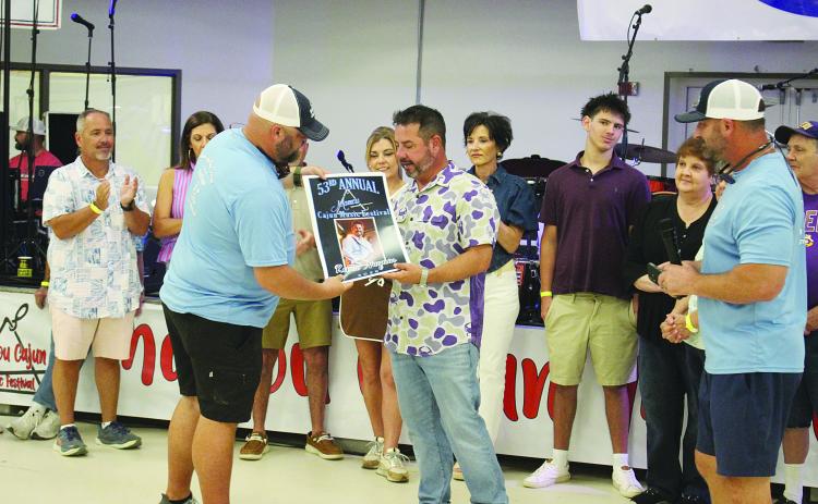 Kevin Naquin (right) accepts his commemorative poster from Mamou Cajun Music Festival Association Vice President Kade Verrette (left). (Gazette photo by Tony Marks)