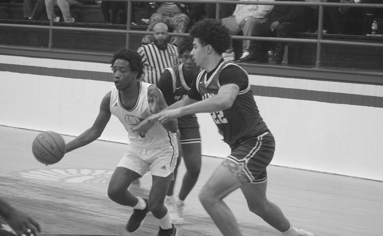Mamou’s Shay Collins defends against Oakdale’s Leon Posey V (2) in the Green Demons’ 65-63 win against the Warriors last Friday night. (Gazette photo by Tony Marks)