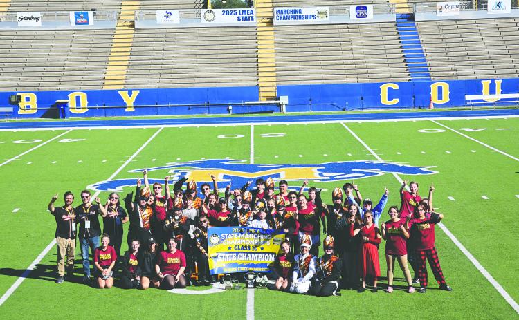 The Pine Prairie High School Marching Band recently ended their season on a high note by capturing  the LMEA State Championship for second year in a row. The group, in the above photo, gathers around the championship banner. (Photo courtesy of Lynette Hazelton)