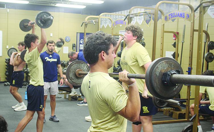 Sacred Heart head football coach Jacob Aguillard (center left) looks on as members of his team lift weights during summer workouts on Tuesday, June 9. (Gazette photo by Tony Marks)