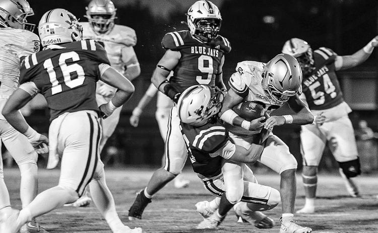 Sacred Heart runner Gavin Patin (22) drags a St. Edmund defender with him as he fights for additional yardage against the Blue Jays. (Photo by Dwight Jodon)